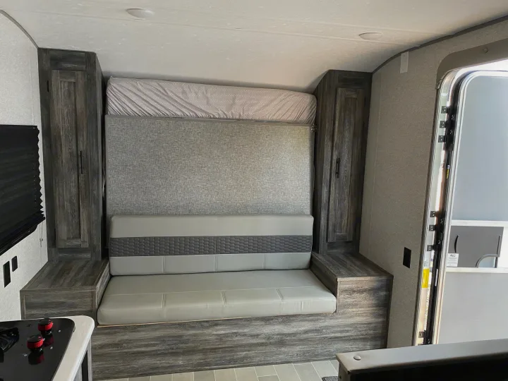 Modern RV rental interior with convertible sofa bed, ample storage, and compact kitchen. Ideal for travel.. Forest River Salem FSX 2021