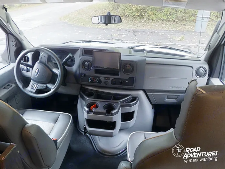 Inside this RV rental, the driver's cockpit is seen, featuring the dashboard, steering wheel, and front seats.. Forest River Sunseeker 2022