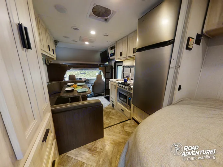 Bright RV rental interior showing a kitchen with stainless fridge, dinette, and sleeping area. Great for adventures.. Forest River Sunseeker 2022