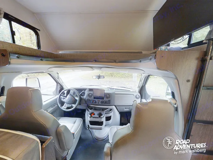RV rental interior: View of the driver's cab, front seats, and overhead bunk, ready for road trip adventures.. Forest River Sunseeker 2022