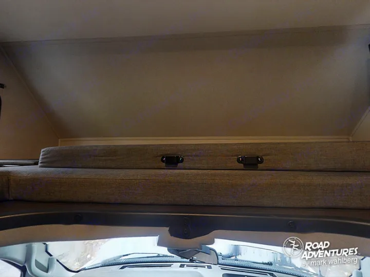 Cozy cab-over bunk in an RV rental, complete with gray cushions and secure latches.. Forest River Sunseeker 2022