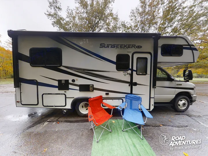 Explore with this RV rental! A Sunseeker Class C RV parked with two chairs on a wet autumn day, ready for travel.. Forest River Sunseeker 2022