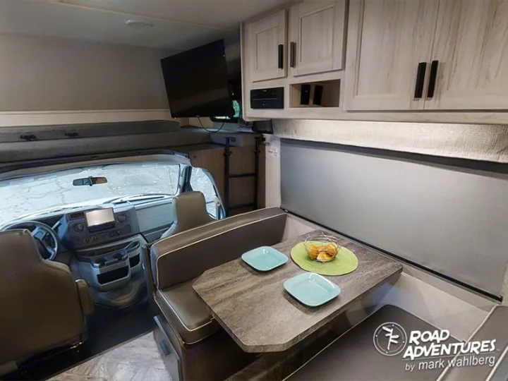 This RV rental interior features a cozy dinette, overhead bed, and driver's cockpit, perfect for road adventures.. Forest River Sunseeker 2022