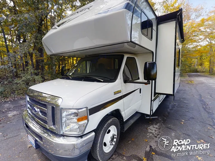 This white Class C RV rental, a motorhome with an extended slide-out, is parked in fall foliage, ready for adventure.. Forest River Sunseeker 2022