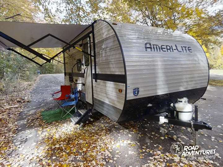 RV rental ready: Ameri-Lite travel trailer with awning extended, chairs set for autumn camping.. Gulf Stream Amerilite 2021