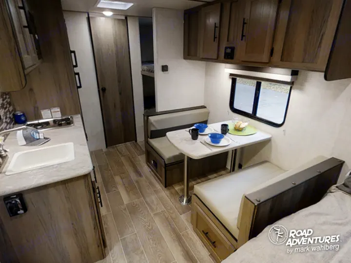 Explore this RV rental interior: a compact kitchen, dinette, and bunk beds provide comfort for your travel adventures.. Gulf Stream Amerilite 2021