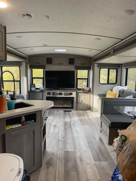 Bright & spacious RV rental interior: modern living area with TV/fireplace, kitchen island, and comfy dinette. Enjoy the open road!. Keystone RV Springdale 2021