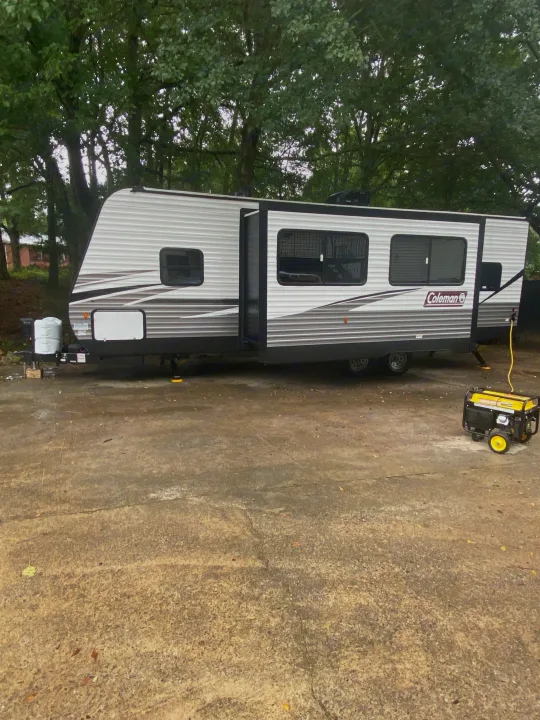 Spacious Coleman RV rental with generator, parked on concrete amidst trees. Ready for adventure!. Coleman Lantern 2021