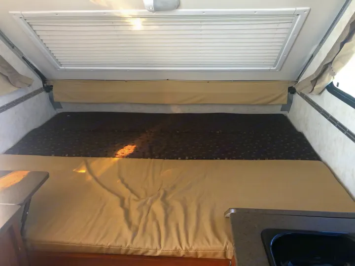 Comfortable RV rental interior: spacious bed, overhead blinds, & kitchenette area for your next adventure.. A Liner A Liner Popup Trailer 2014