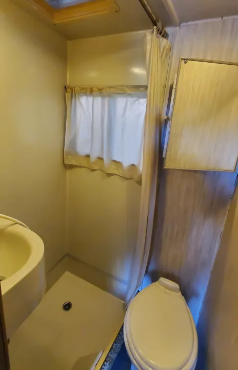 RV rental bathroom interior: Compact layout includes sink, toilet, shower area with curtain and floor drain.. Lazy Daze 22 1987