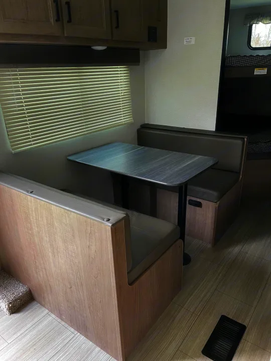 RV rental dinette with cozy benches, a table, and bunk beds in the background, offering a comfortable space.. Keystone Hideout 2021