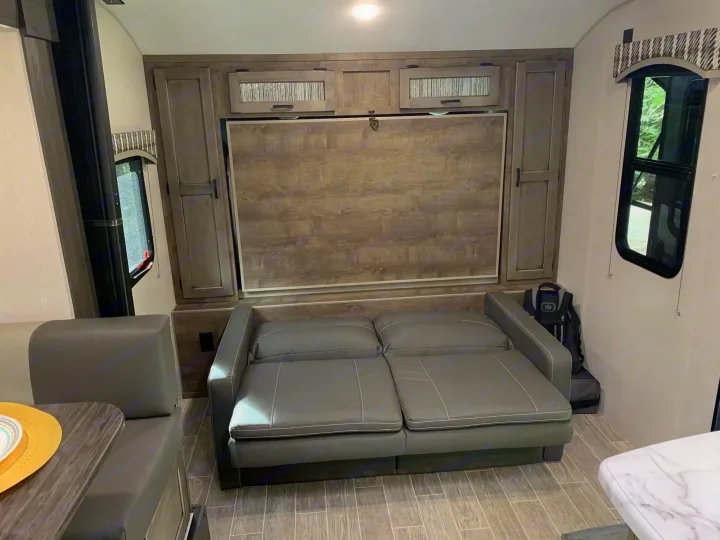 Inside an RV rental: a convertible sofa, wall-mounted murphy bed, and dinette maximizing compact living space.. Sonic Sonic Trailer 2025