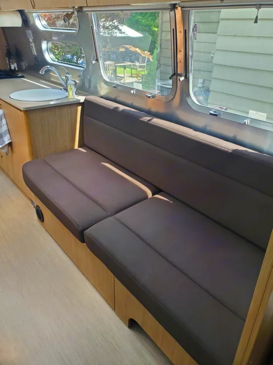 RV rental: Modern travel trailer interior with comfy dinette seating, kitchen sink, and large windows revealing a backyard.. Airstream Flying Cloud 2018