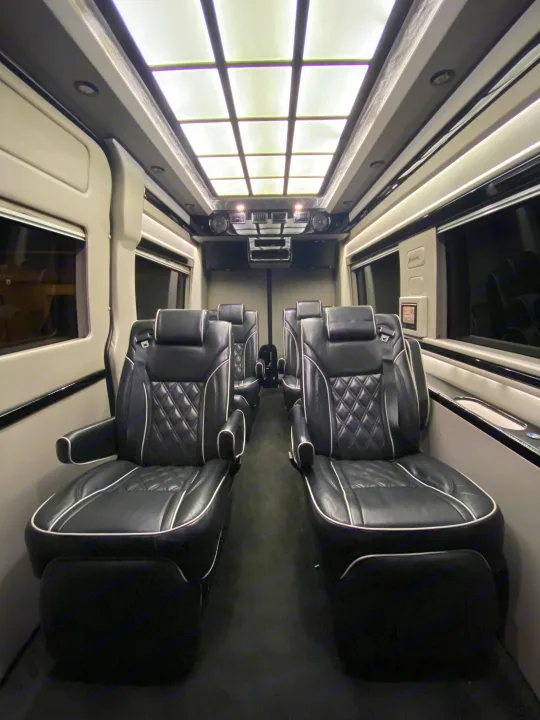Luxurious RV rental interior featuring black leather seats with white piping, illuminated window panels, and a control console.. Mercedes-Benz MB140 2015