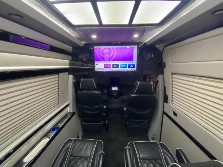 Luxury RV rental interior featuring black leather seats, large screen entertainment, and purple ambient lighting.. Mercedes-Benz MB140 2015