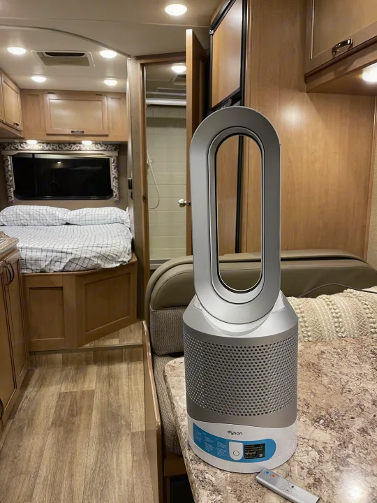 A Dyson air purifier rests on the counter of an RV rental, showcasing the compact interior with a bed and bathroom.. Thor Four Winds 2019