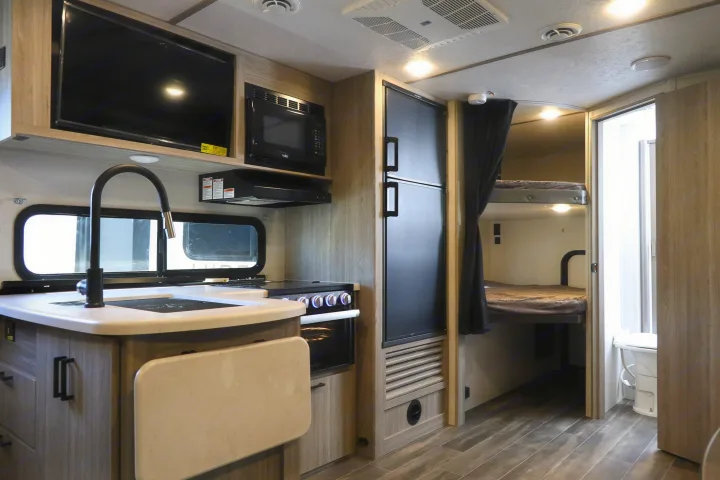 Explore this modern RV rental interior featuring a full kitchen with appliances, an extendable counter, and comfortable bunk beds. Includes bathroom.. KeyStone Passport SL 221BH 2022