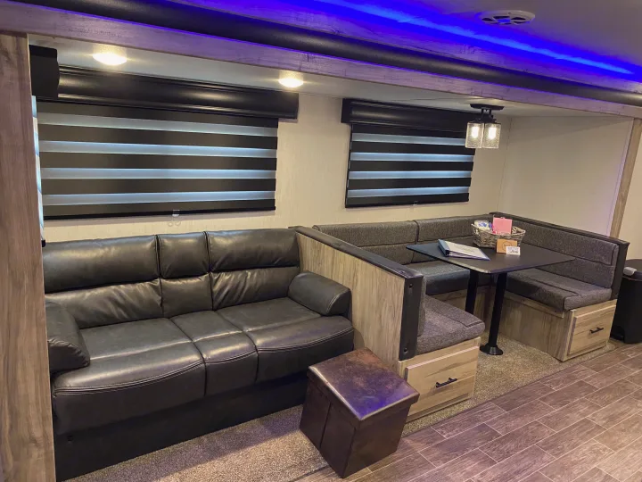 Spacious RV rental living area with comfy leather sofa, dinette, modern blinds, and ambient blue lighting.. Forest River Cherokee Alpha Wolf 2021