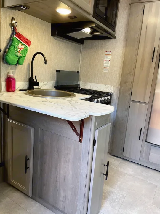 RV rental's modern kitchen with sink, gas stove, microwave, and a clever extendable counter.. Forest River Coachmen Freelander 2021