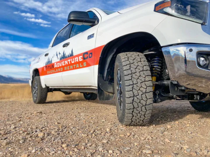 Angled view of a white Titus Adventure Co. overland truck on a gravel road. Perfect for your RV rental adventure.. Toyota Tundra 2021