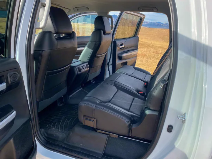Spacious black leather rear passenger seats & durable floor mats in an SUV, ready for your rv rental adventure.. Toyota Tundra 2021