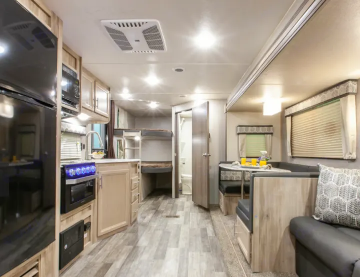 Spacious RV rental interior with modern kitchen, dining booth, comfy sofa, and bunk beds. Perfect for family adventures.. Forest River Coachmen Catalina Legacy 2021