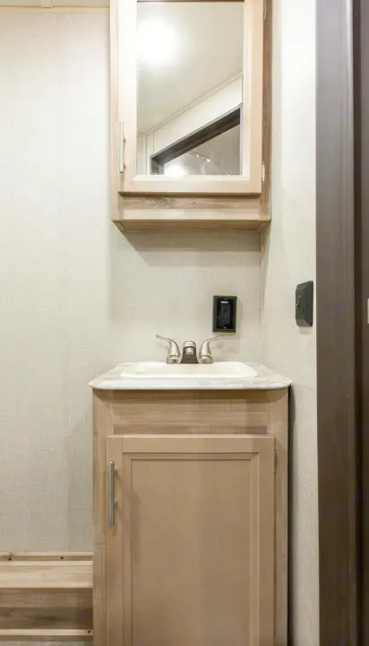 An RV rental's compact bathroom features a vanity, sink, medicine cabinet with mirror, and electrical outlet.. Forest River Coachmen Catalina Legacy 2021