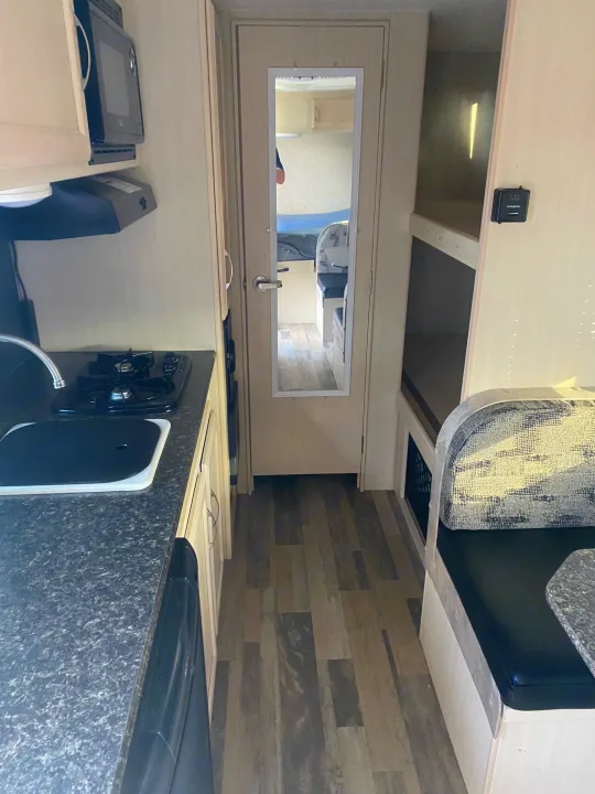 Compact RV rental interior featuring a functional kitchen area with stove, sink, and microwave. Perfect for travel.. Winnebago Micro Minnie 2018