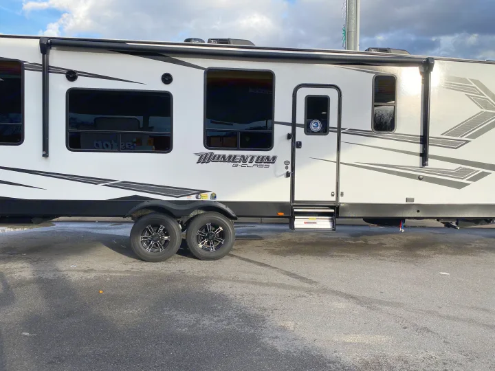 White Momentum G-Class travel trailer RV rental with sleek black graphics, multiple windows, and a side entry.. Grand Design Momentum 2021