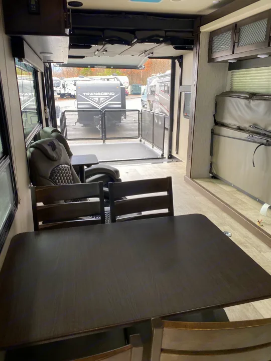 Spacious rv rental toy hauler interior with patio, dining area, and recliners. Bunk beds seen on right.. Grand Design Momentum 2021