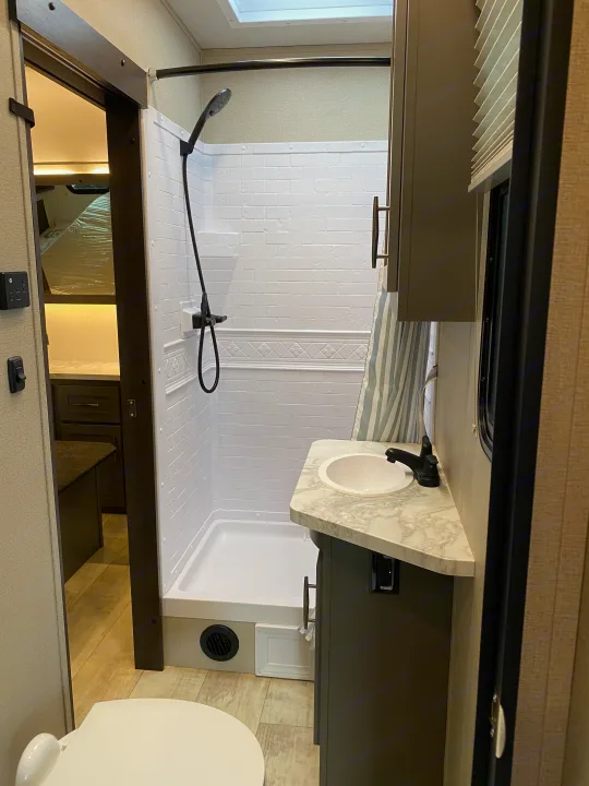 Spacious RV rental bathroom: modern shower, sink, and toilet offer comfort for travel.. Grand Design Momentum 2021