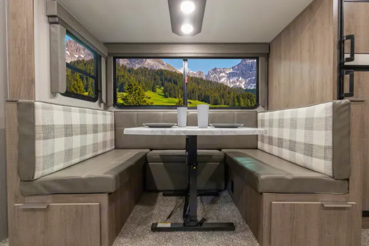 Cozy RV rental dinette featuring comfortable U-shaped seating, storage, and stunning mountain window views.. Grand Design Imagine 2021