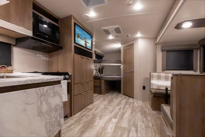 Bright RV rental interior featuring a kitchen, bunk beds, and dinette area for comfortable trips.. Grand Design Imagine 2021