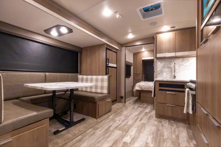 Modern RV rental interior: U-shaped dinette, full kitchen, and a peek into the bedroom. Ready for adventures!. Grand Design Imagine 2021