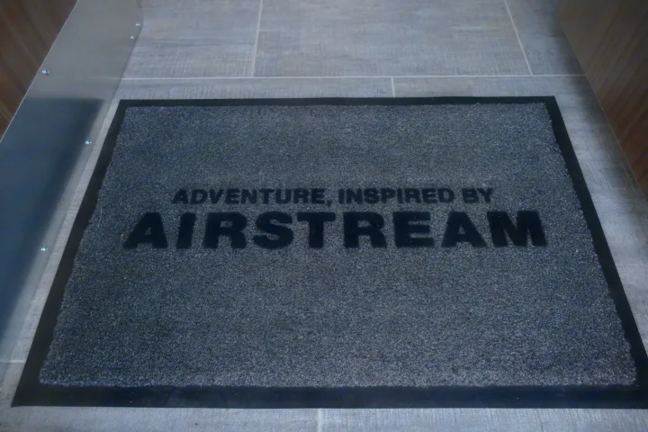Inside an RV rental, a grey Airstream welcome mat reads 'ADVENTURE, INSPIRED BY AIRSTREAM' on a tiled floor.. Airstream Caravel 2020