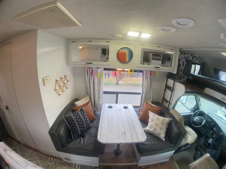 Spacious RV rental interior: modern dining booth, overhead storage, and driver's area view. Ready for comfortable travel!. Tioga Other 2006