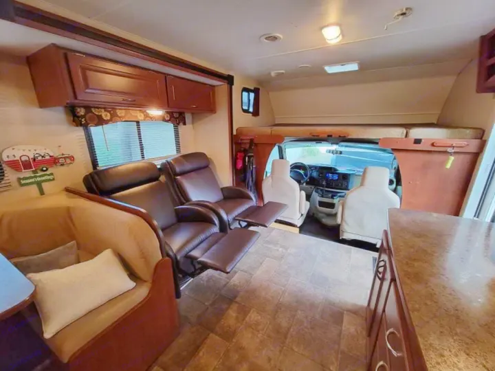 Spacious RV rental interior: living area with recliners, couch, kitchen, and front cabin with overhead bunk bed.. Winnebago Minnie Winnie 2014