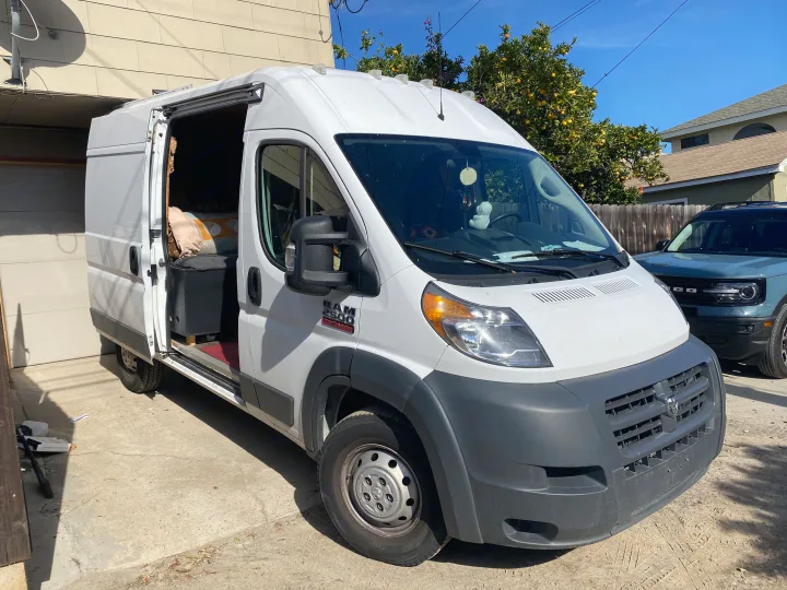White Ram ProMaster RV rental, a converted camper van, with its side door open, parked in a sunny driveway.. Dodge Ram Promaster 2500 2017