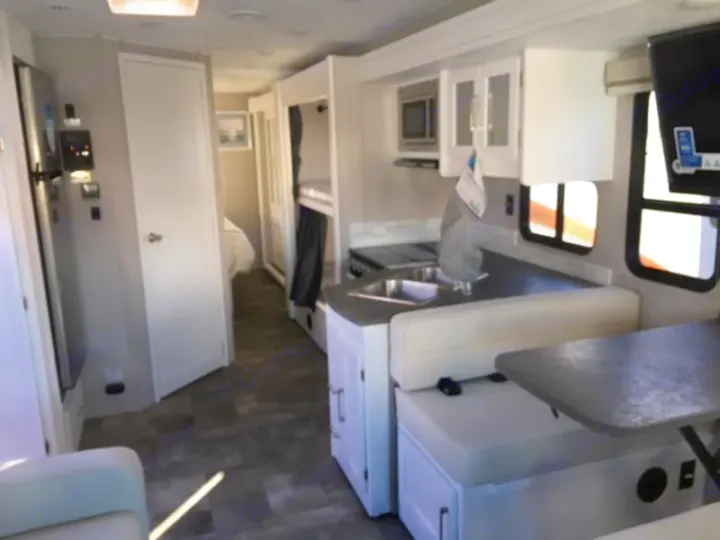 View of a modern RV rental's spacious interior, featuring a kitchen, dining area, bunk beds, and a rear bedroom.. Forest River Coachmen Pursuit 2022