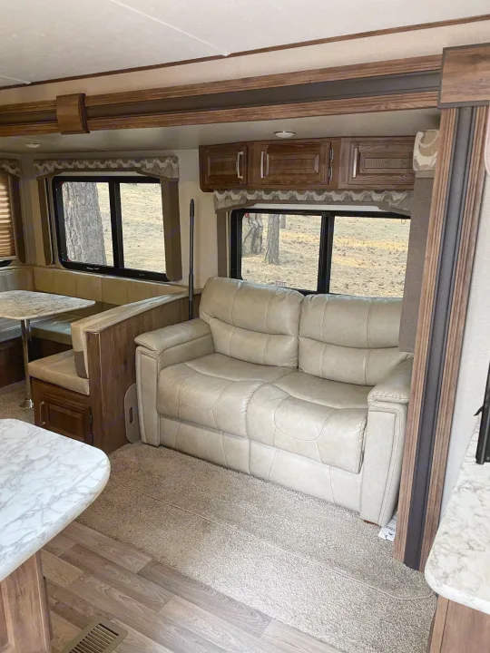 Inside an rv rental: inviting living space with light sofa, dinette, and large windows revealing the outdoors.. Keystone Cougar Half-Ton 2017