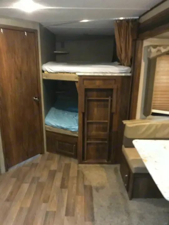 Cozy bunkhouse style RV rental interior featuring comfortable beds and a dinette area, ideal for family travel.. Keystone Cougar Half-Ton 2017