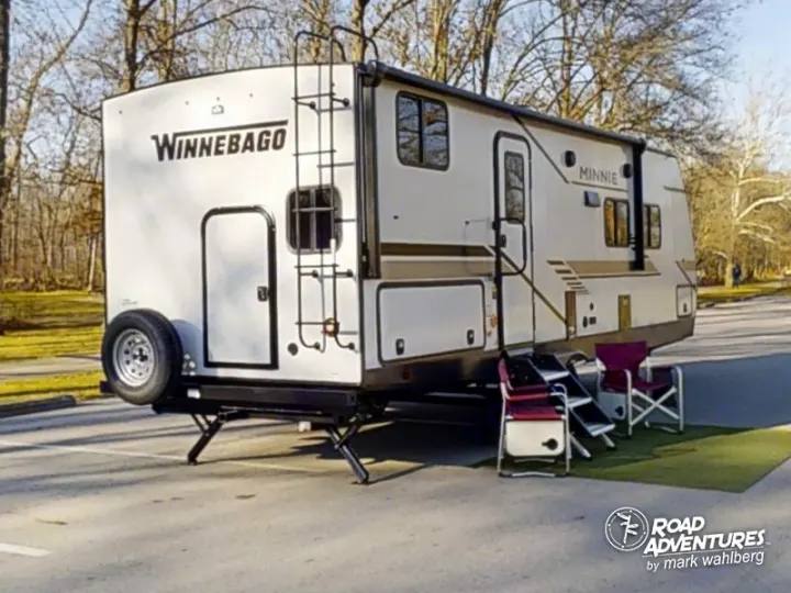 An RV rental: Winnebago Minnie travel trailer, parked with camping chairs & mat, ready for outdoor adventure.. Winnebago Minnie 2301BHS 2022