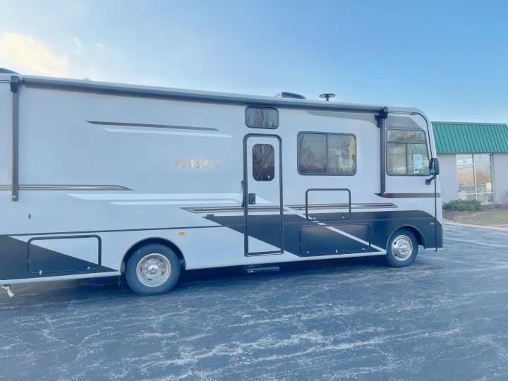 Detailed view of a modern gray and black Pursuit motorhome, ideal for an rv rental. Parked on asphalt under blue sky.. Forest River Coachmen Pursuit 2022