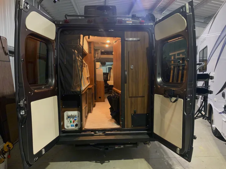 View into a well-appointed camper van's interior through its open rear doors, suitable for an RV rental adventure.. Winnebago Travato 2022