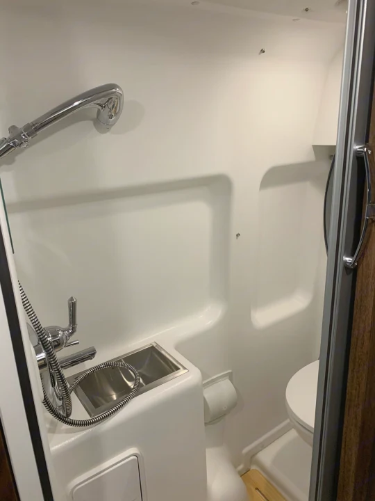 Compact RV rental wet bath with integrated shower, toilet, and sink, maximizing space.. Winnebago Travato 2022