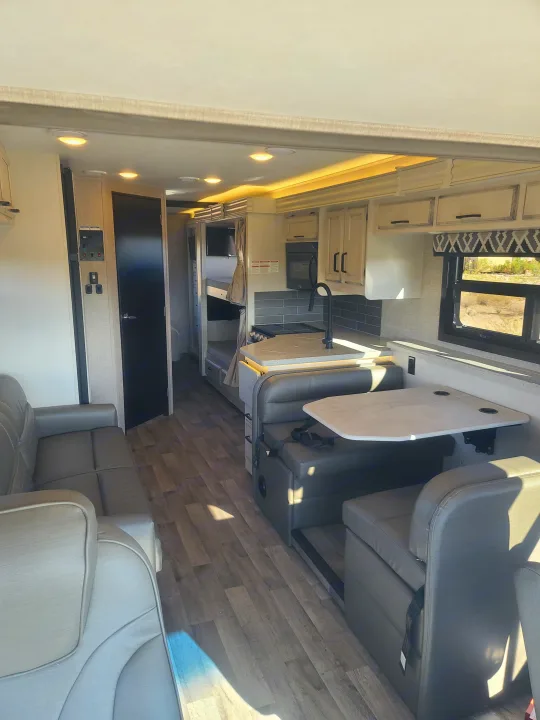 Bright RV rental interior showing a full living space with kitchen, dinette, and bunk beds, ready for travel.. Entegra Vision 29F 2022