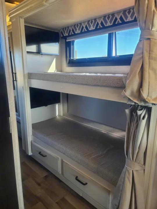 Cozy RV rental interior featuring modern bunk beds with built-in storage and individual TVs.. Entegra Vision 29F 2022