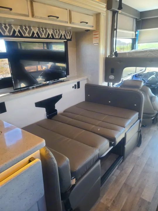 An RV rental interior featuring a modern dinette area with cushioned seating, a TV, and a versatile table.. Entegra Vision 29F 2022