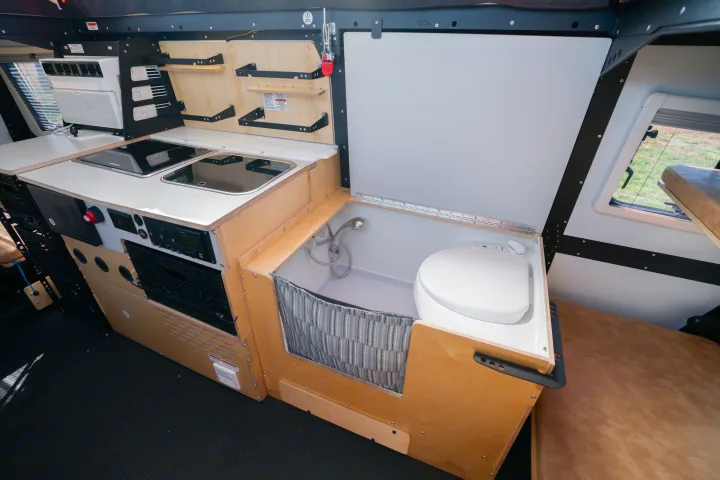Compact RV rental interior: kitchen with stove/sink, AC, and a small integrated shower/toilet for efficient living.. TAXA Habitat Mantis 2021
