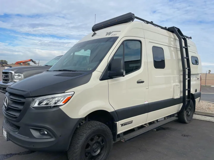 Rugged cream Winnebago Revel camper van, ideal for an adventurous rv rental. Features include roof rack & ladder.. Winnebago Revel 2021